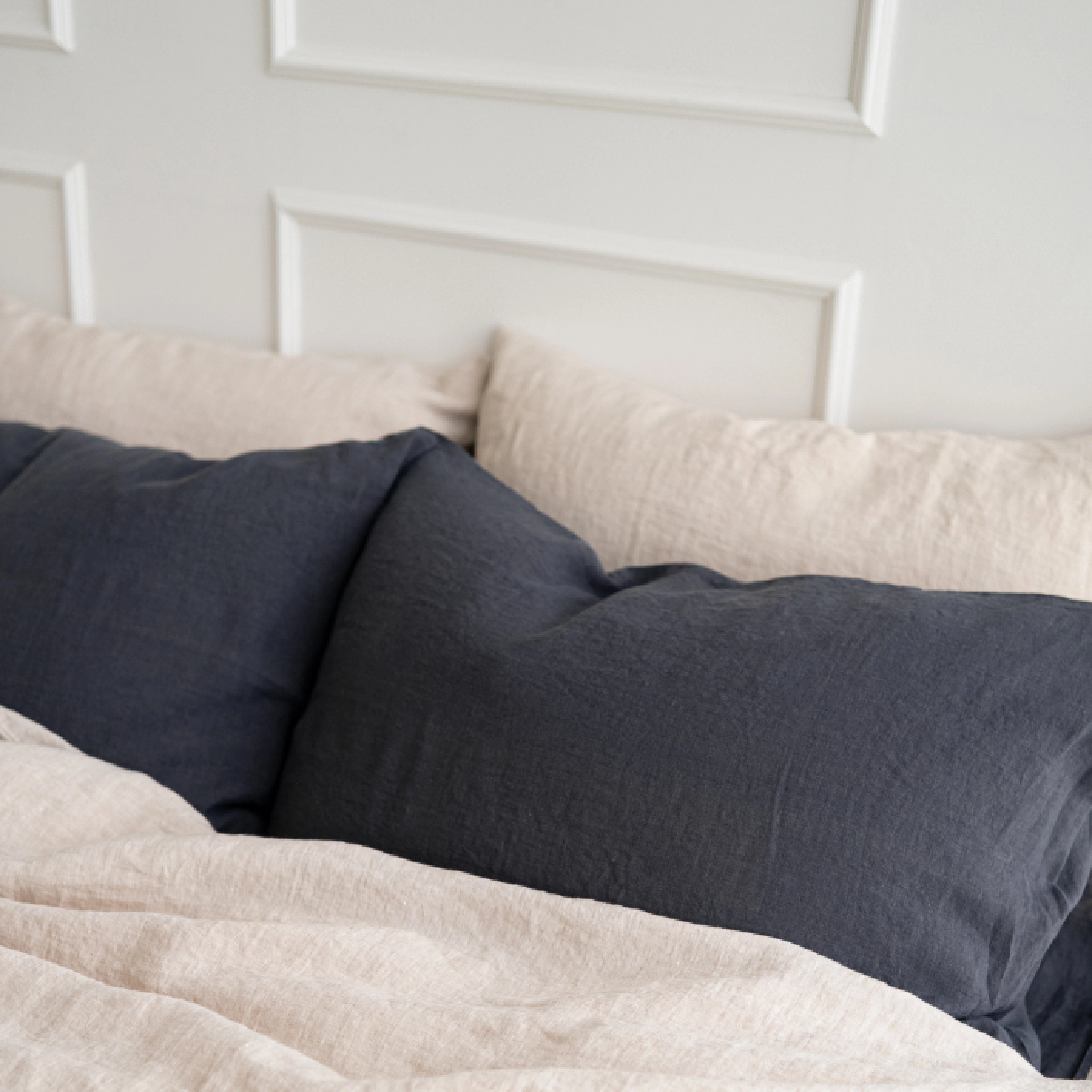 Modern bedroom styled with dark grey stonewashed linen pillowcases and beige bedding