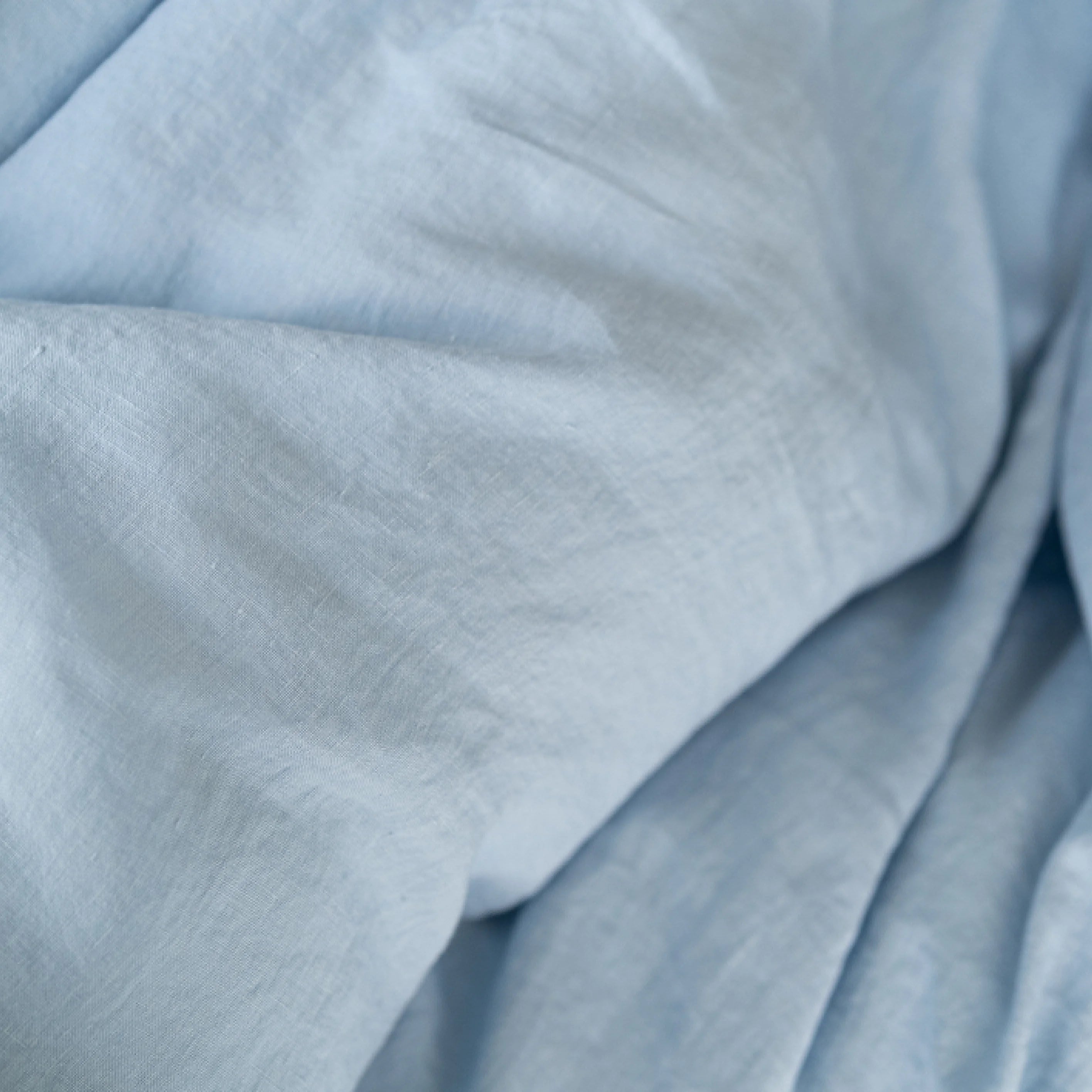 Close-up texture of powder blue stonewashed European flax linen fabric.