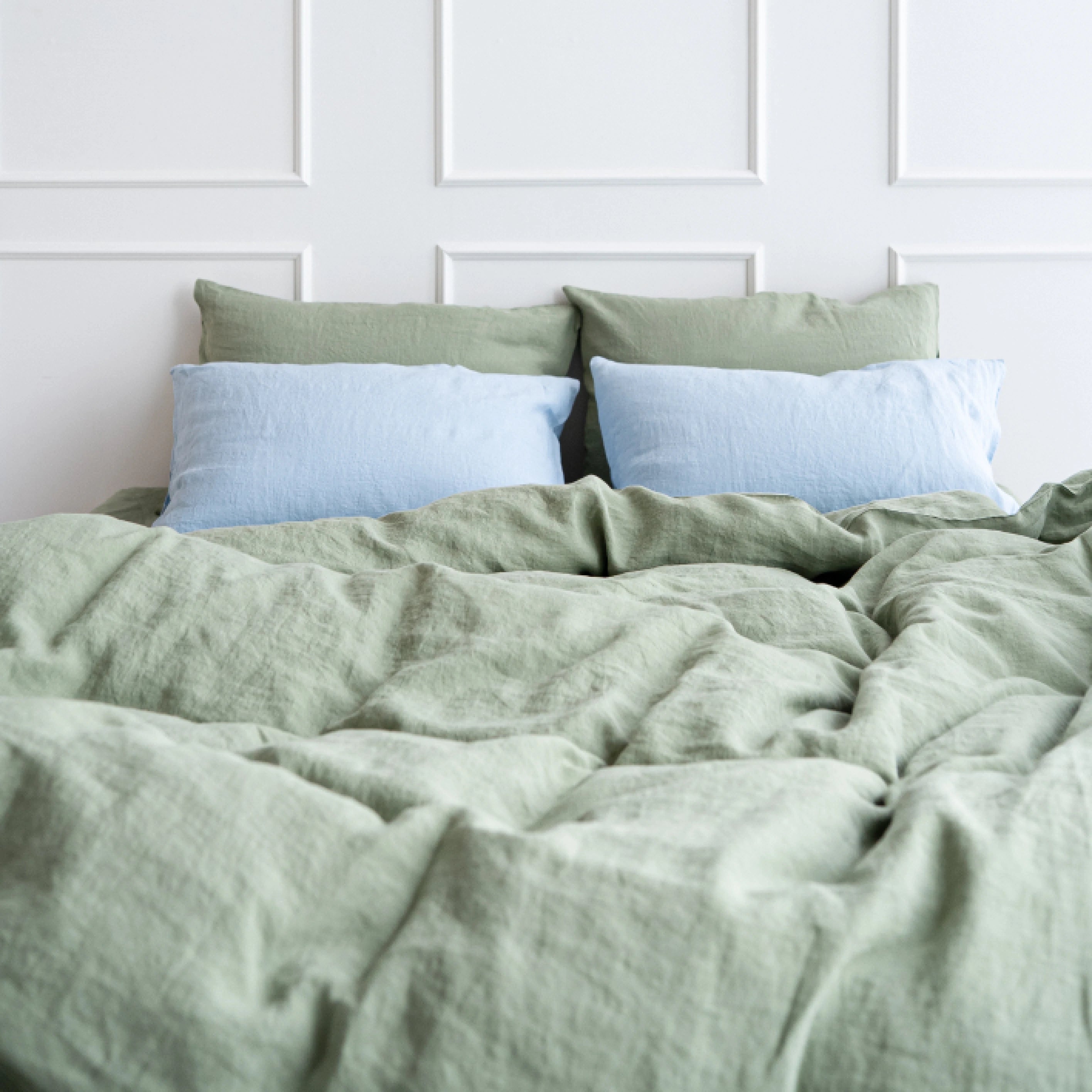 Serene sage green stonewashed linen bedding styled on a bed with powder blue pillows