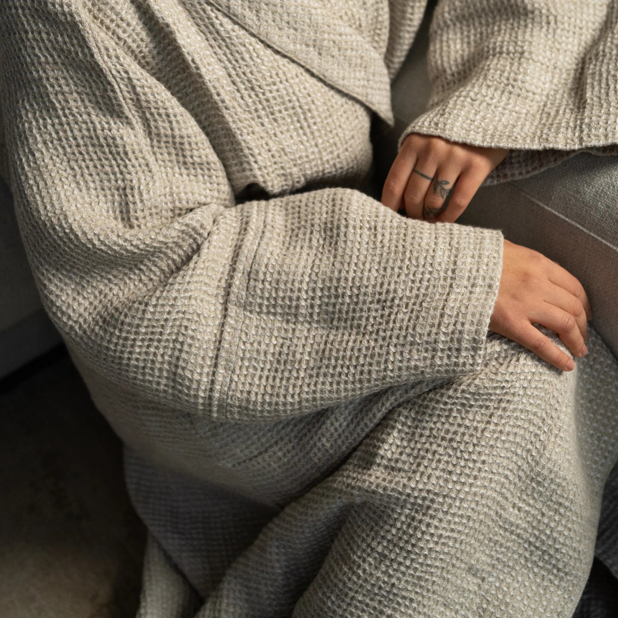 Close-up of beige waffle-textured linen robe showing three-dimensional weave created by beige and white yarns